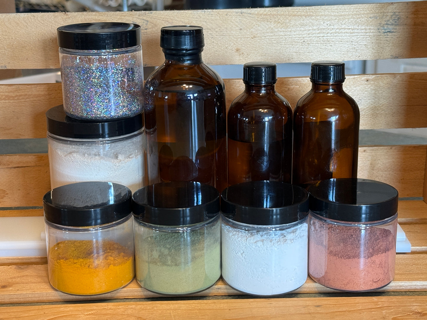 Collection of glass jars and bottles with black lids on a wooden surface