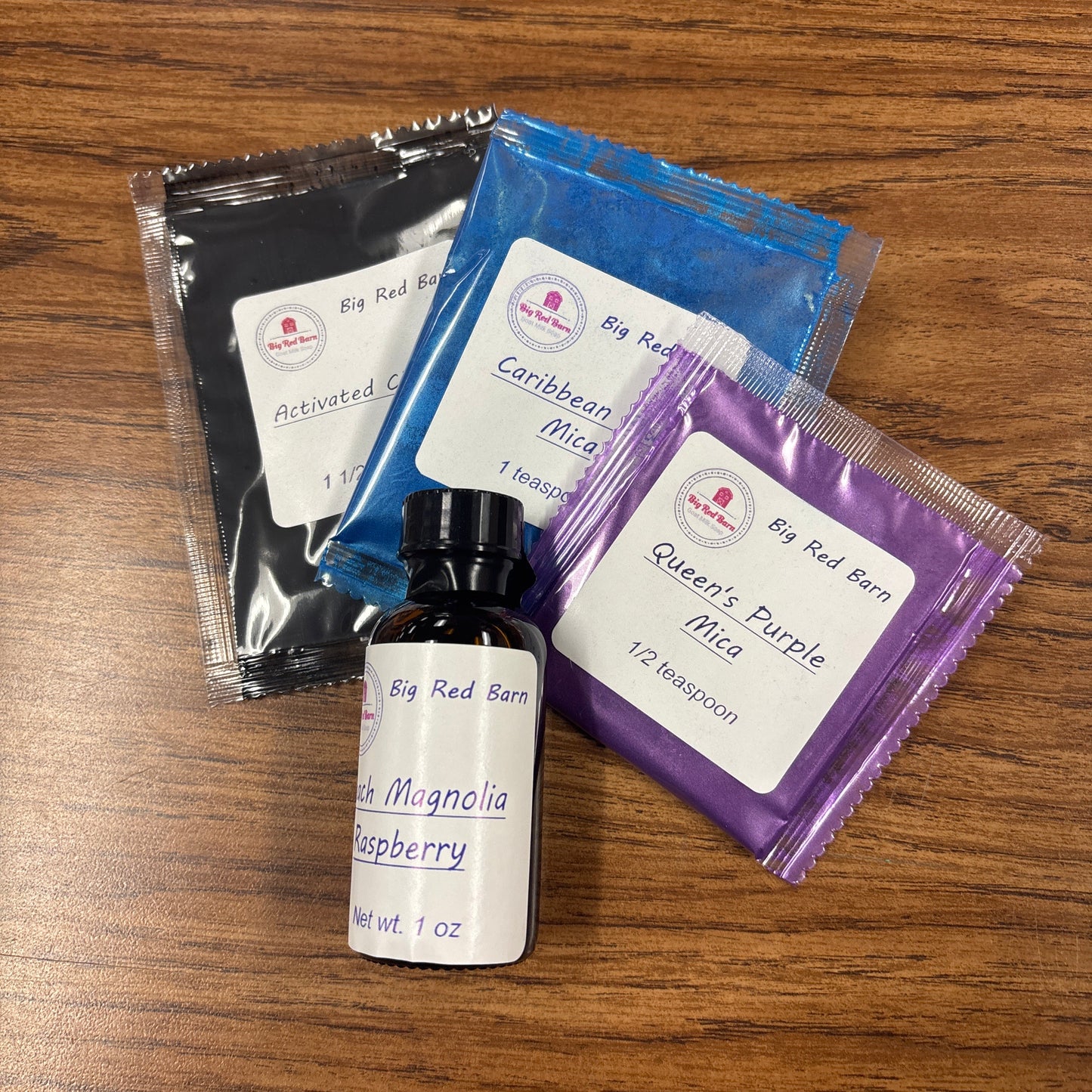 Tipsy Lane Kit with Peach magnolia Raspberry fragrence oil with black, blue and purple colorant kits on a wooden surface