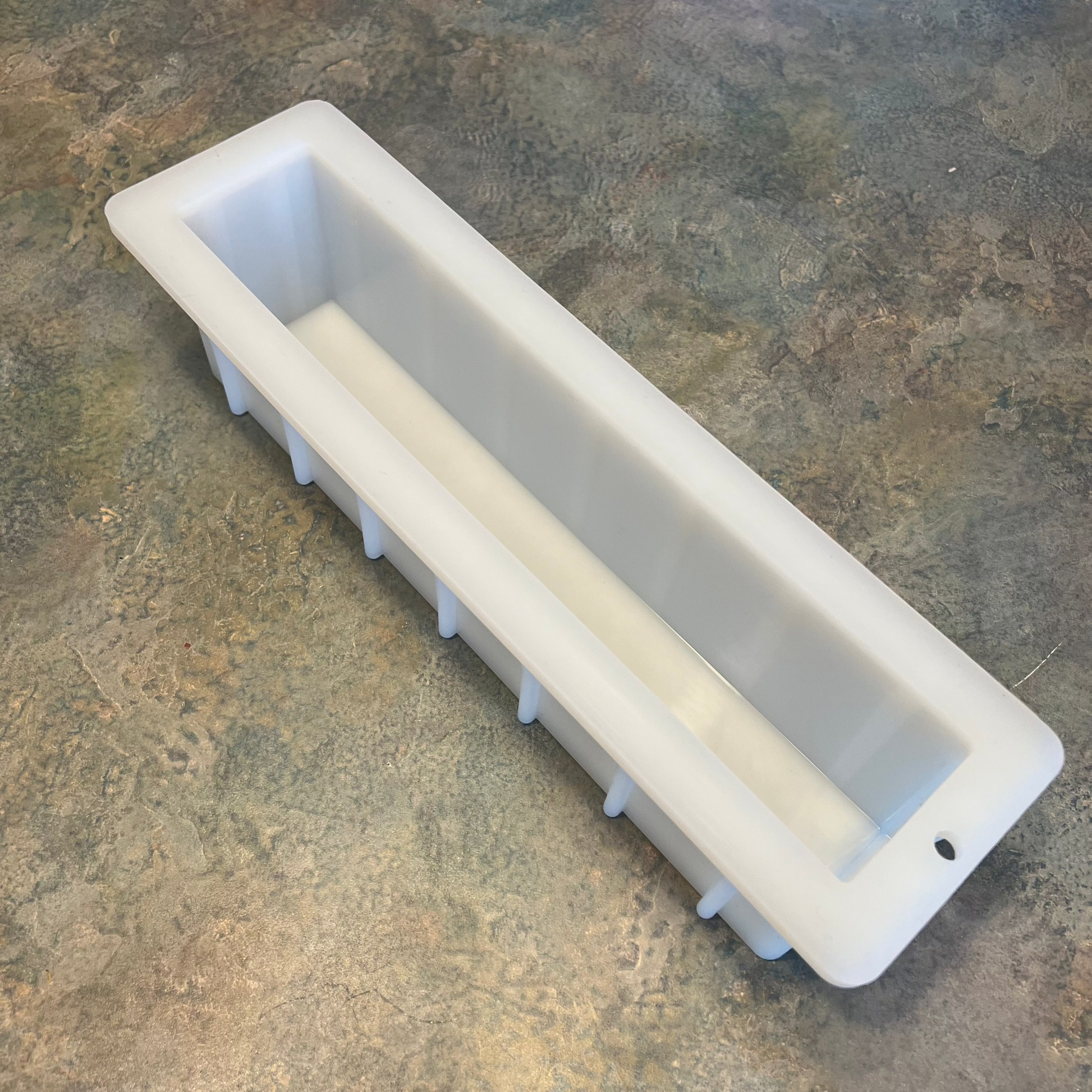 A 12 inch tall white loaf-shaped soap mold on a brown surface.