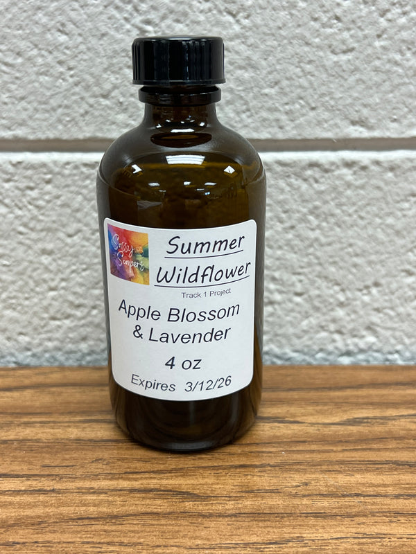 4 oz Bottle of Summer WildFlower Apple Blossom & Lavender fragrance oil on a wooden surface. Expires 3/12/2026