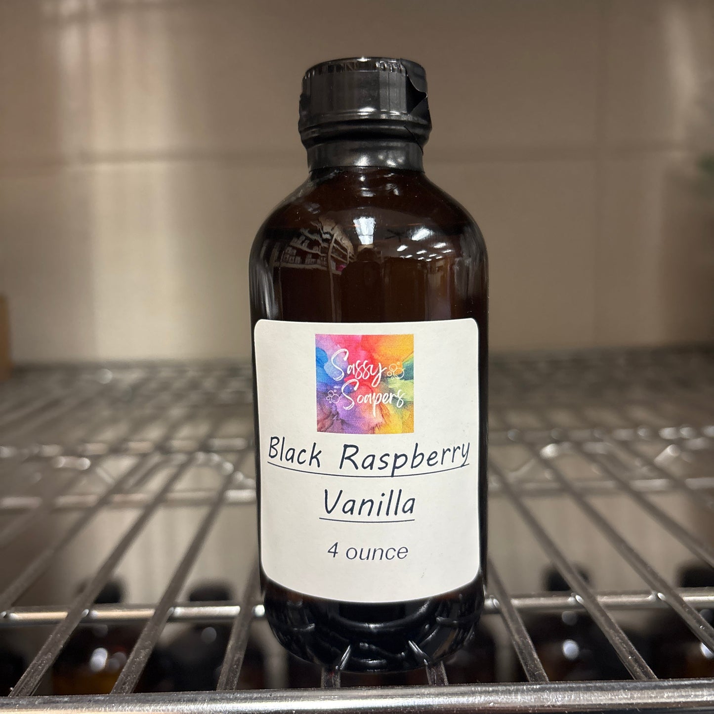 Bottle of Black Raspberry Vanilla fragrence oils with label on a metal surface