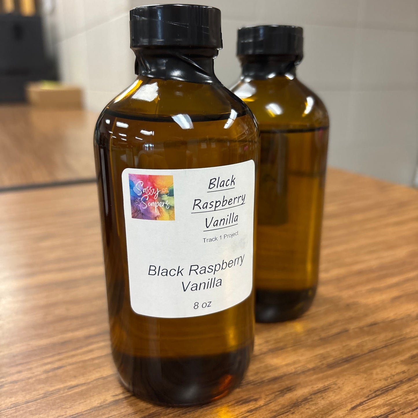 Two bottles of Black Raspberry Vanilla fragrence on a wooden surface