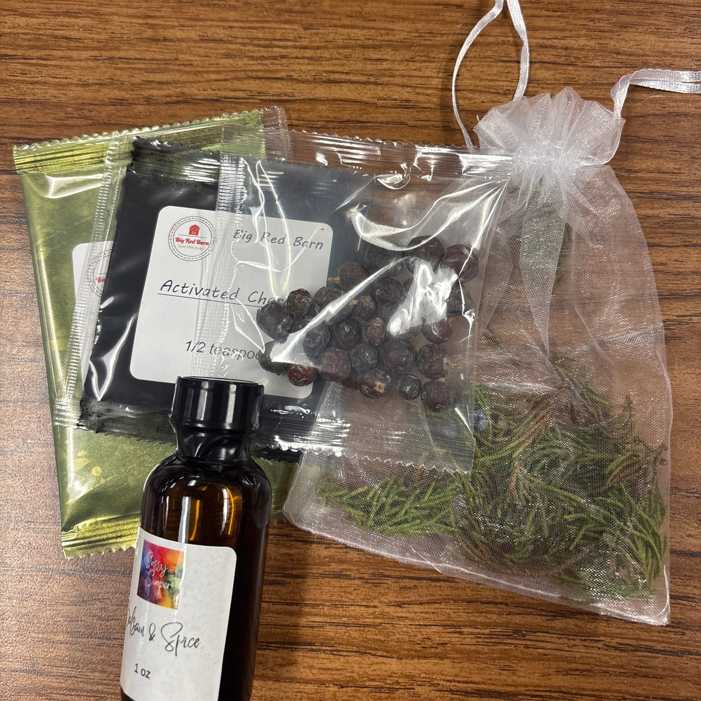 Herbal products including a Balsam and Spice fragrence oil bottle and bags on a wooden surface