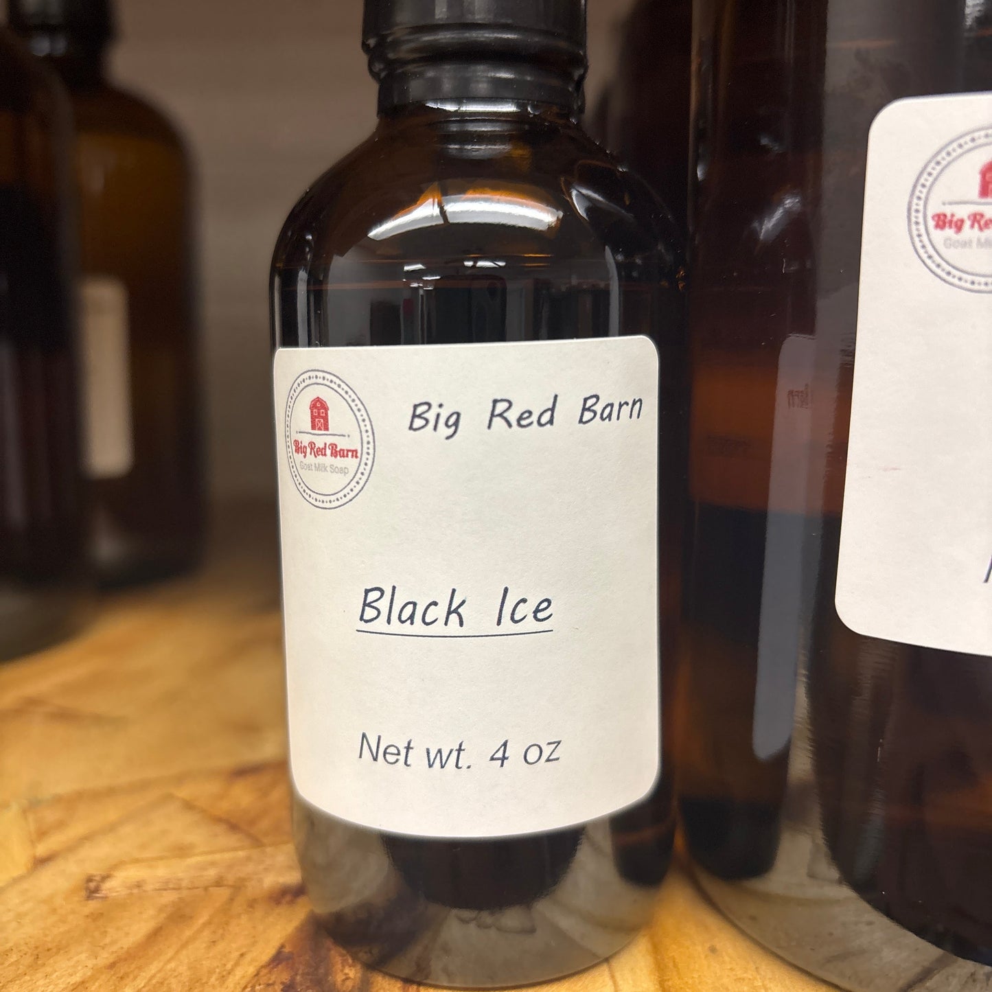 Bottle of Big Red Barn Black Ice fragrance on a wooden surface