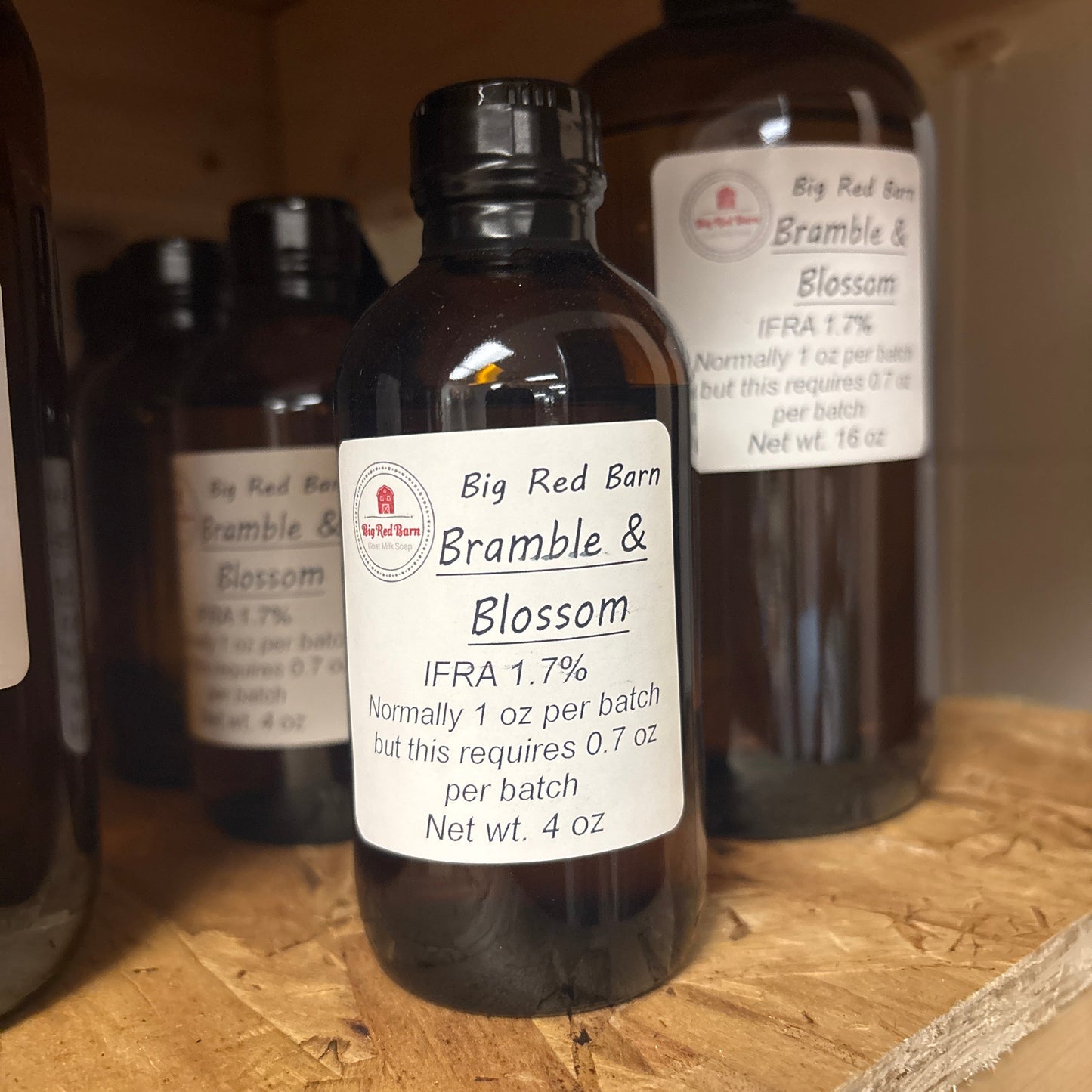 Three bottles of Big Red Barn Bramble & Blossom fragrence oils on a wooden surface
