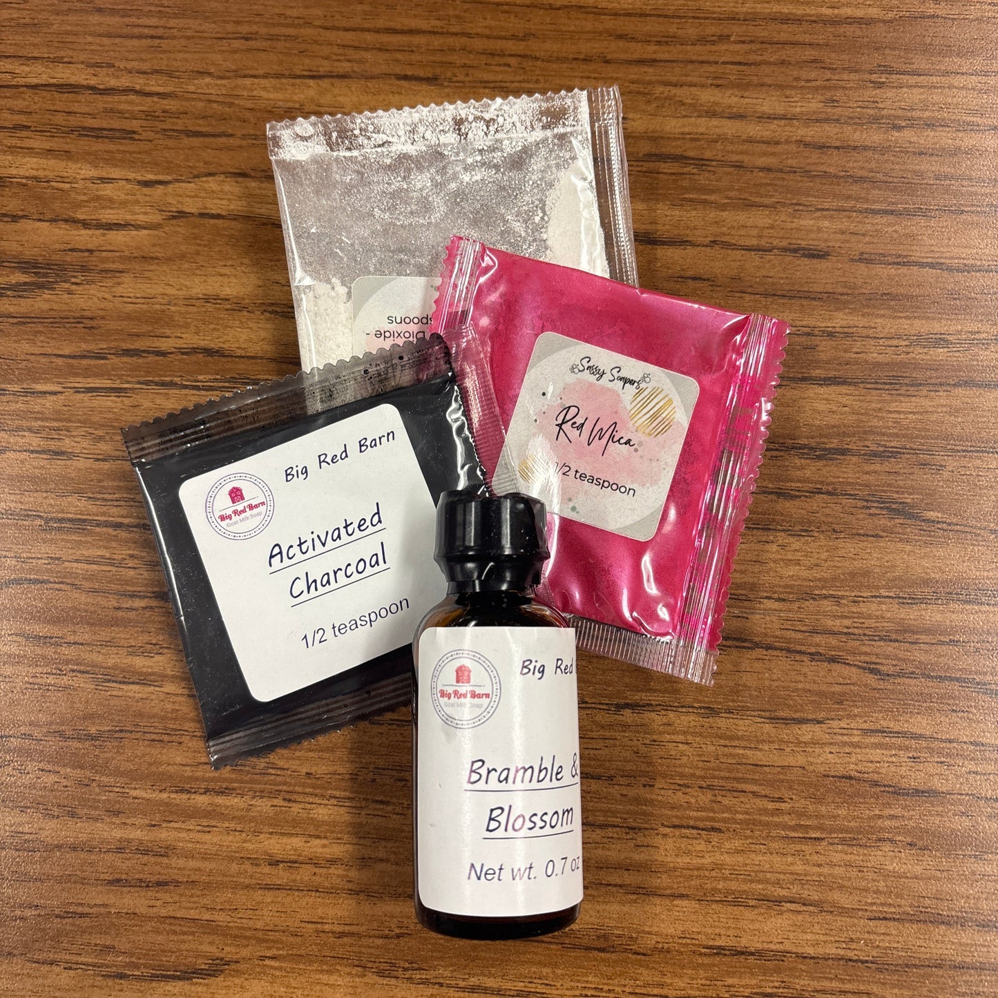 Bramble and Blossom kit including a Bramble and Blossom fragrence oil bottle, packets, and a mirror on a wooden surface