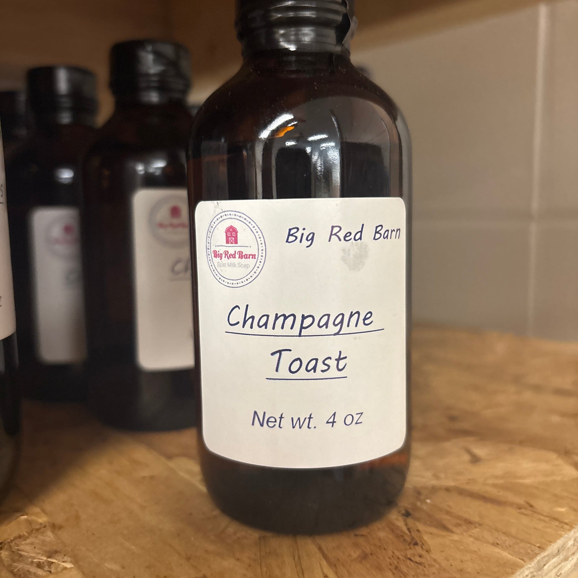Bottle of Big Red Barn Champagne Toast fragrance on a wooden surface
