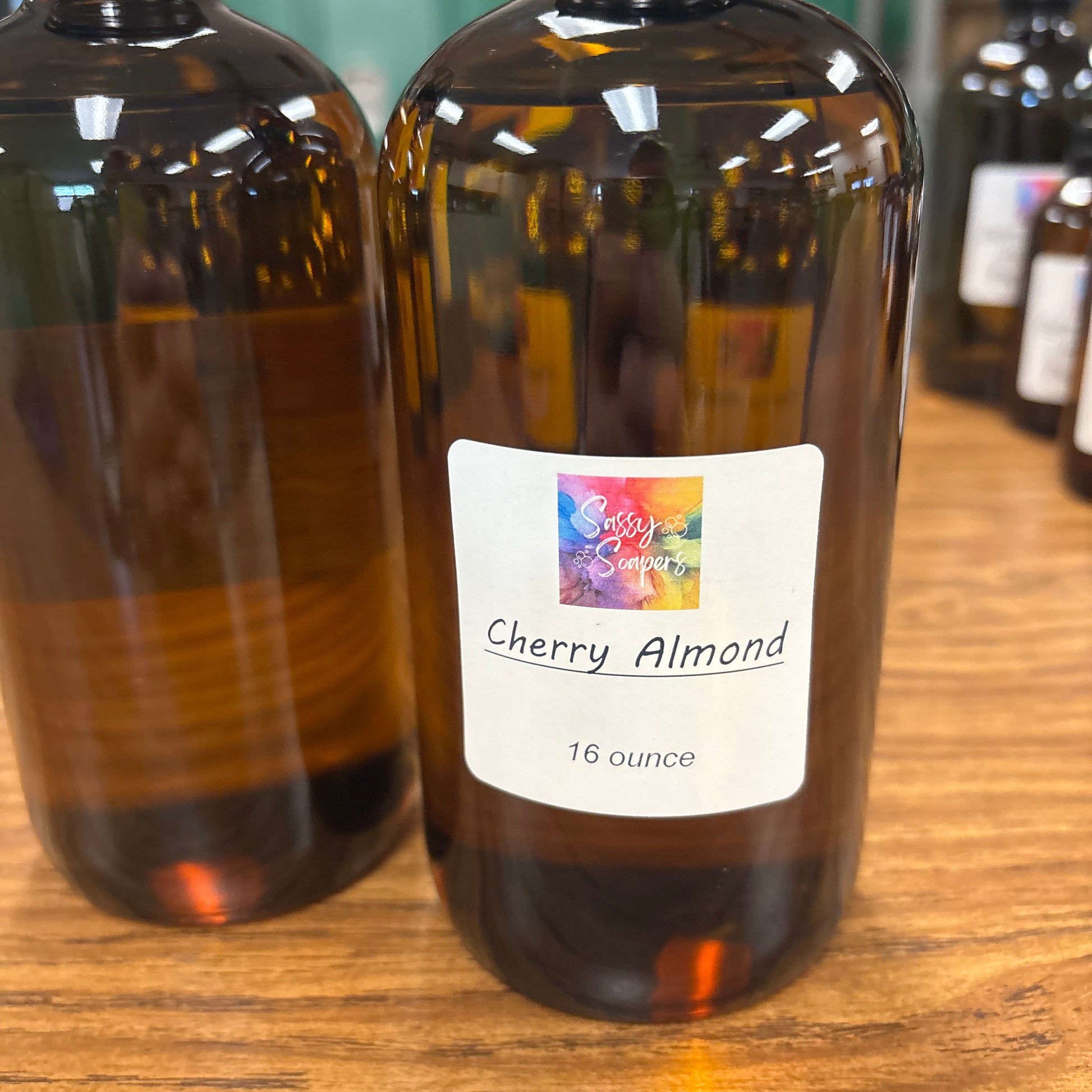 Bottle of Cherry Almond fragrence oils on a wooden surface with a colorful label.