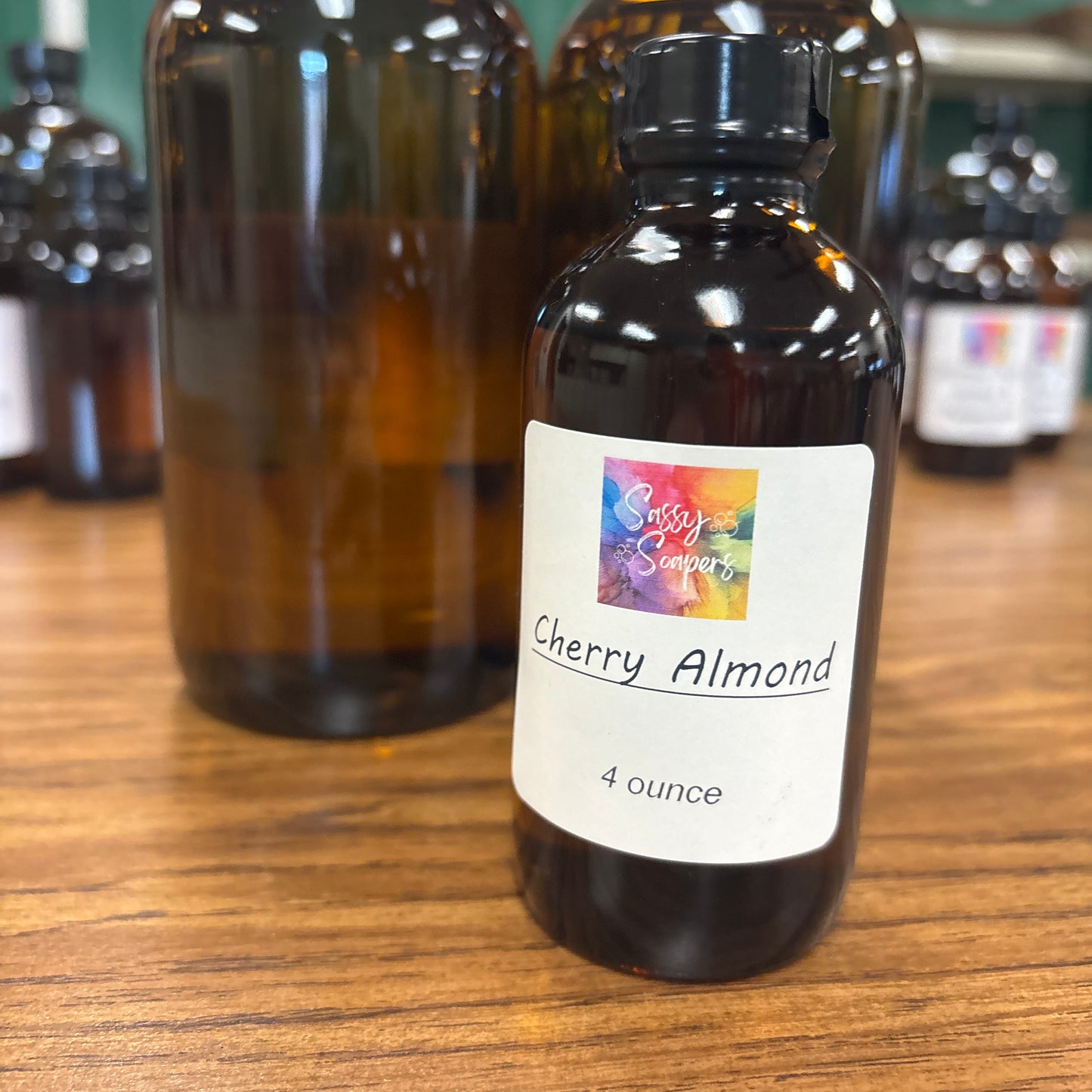 Bottle of cherry almond fragrence oils with a colorful label on a wooden surface