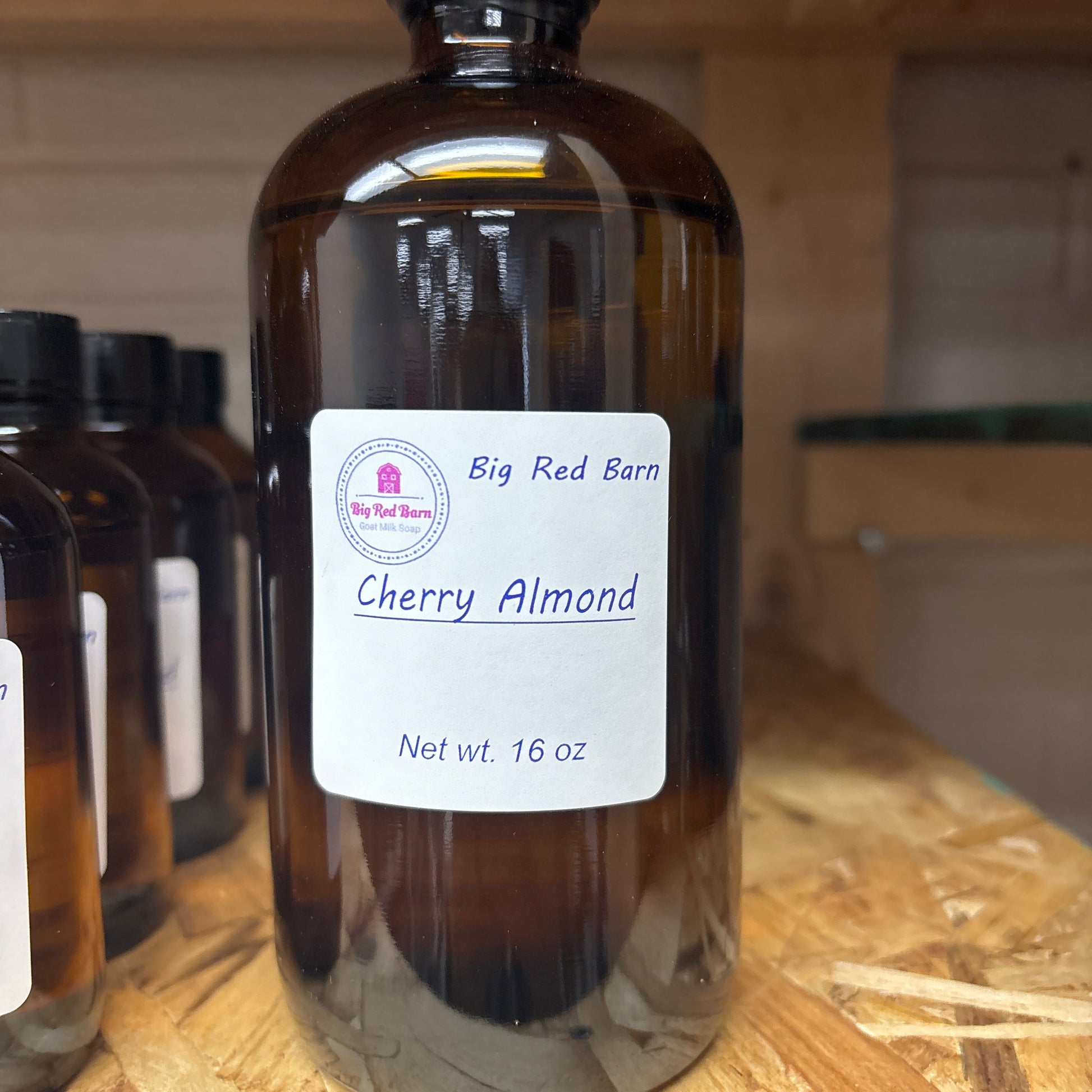 Bottle of cherry almond fragrance oil with a label on a wooden surface