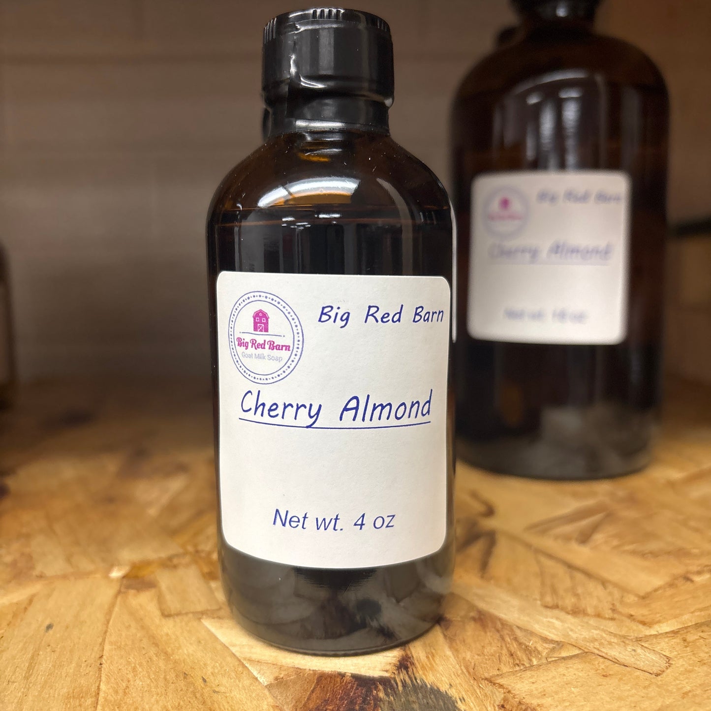 Two bottles of Cherry Almond fragrance on a wooden surface