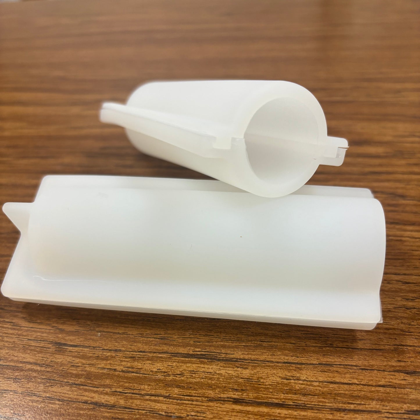 Two white plastic molds designed for crafting embeds, placed on a wooden surface.