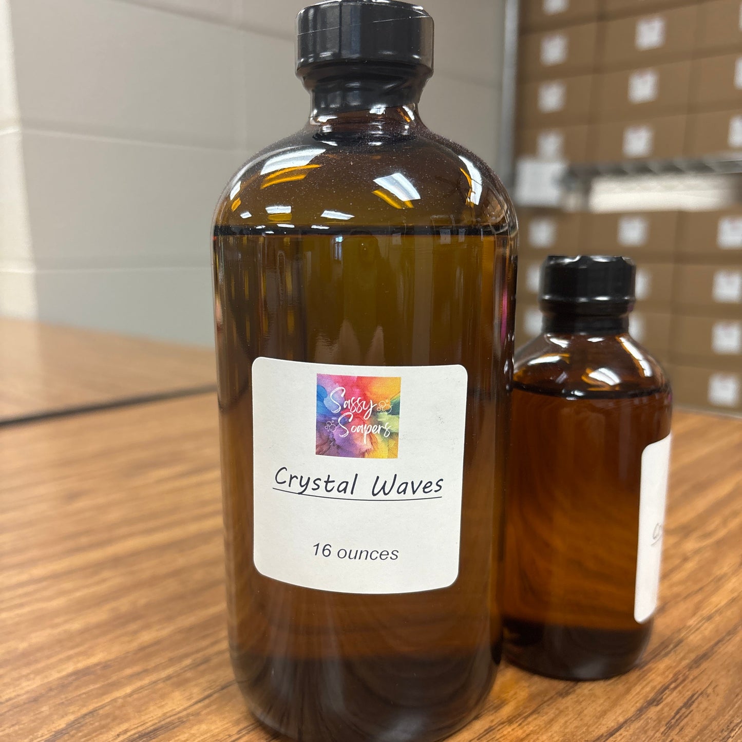 Two brown bottles with Crystal waves fragrence labels on a wooden surface