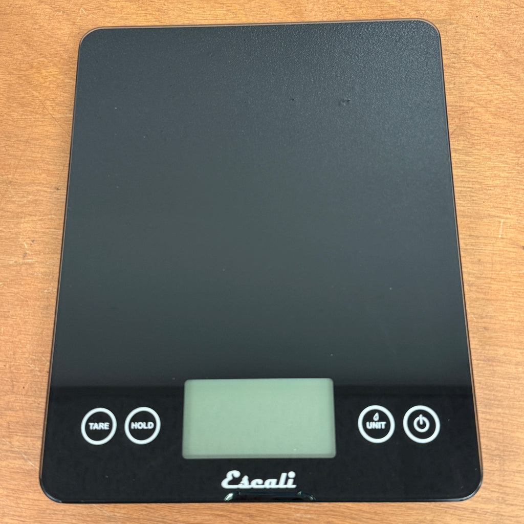 Digital kitchen scale with a black surface and visible brand name on a wooden background