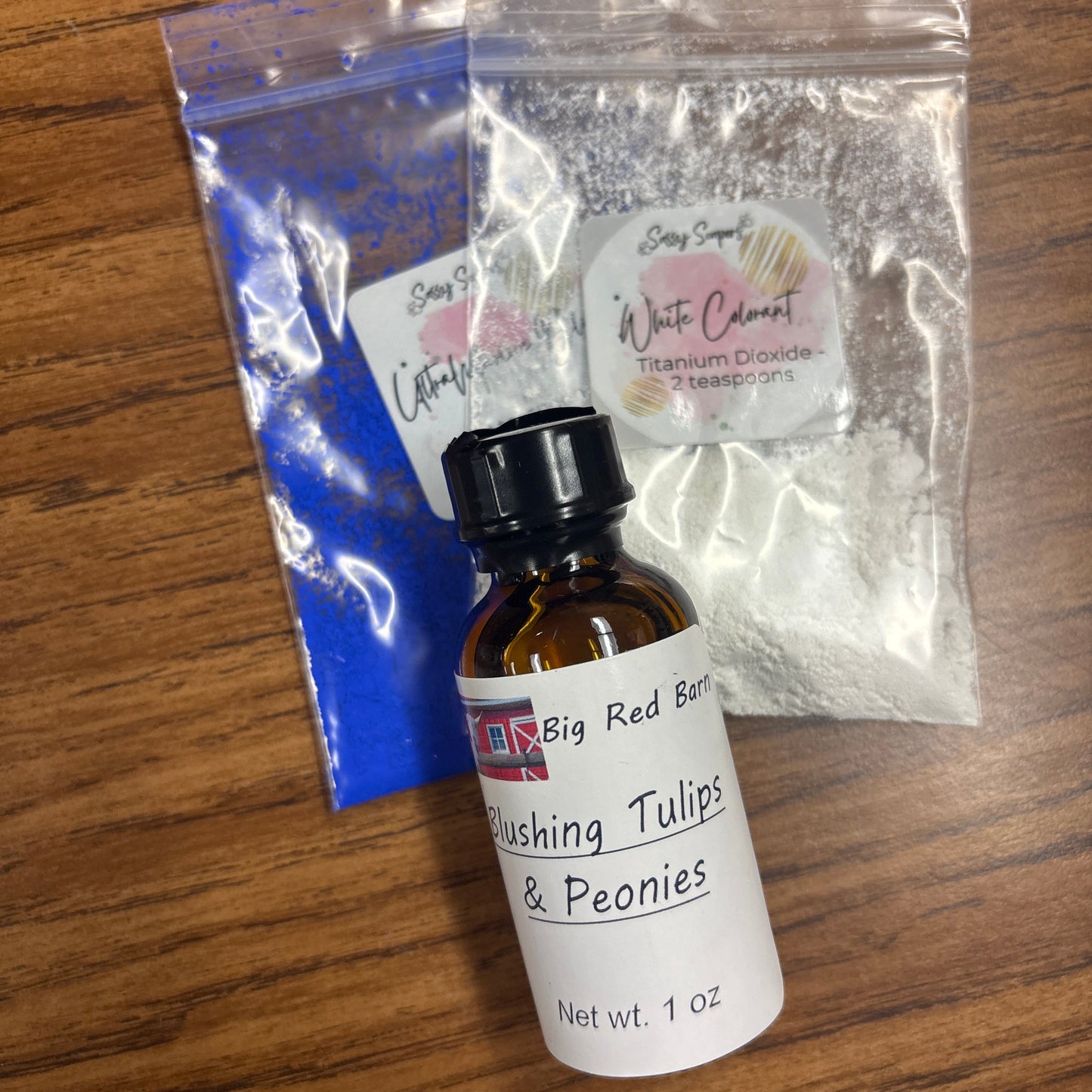 Bottle of 'Blushing Tulips & Peonies' with a small bag of 'White Cement' on a wooden surface