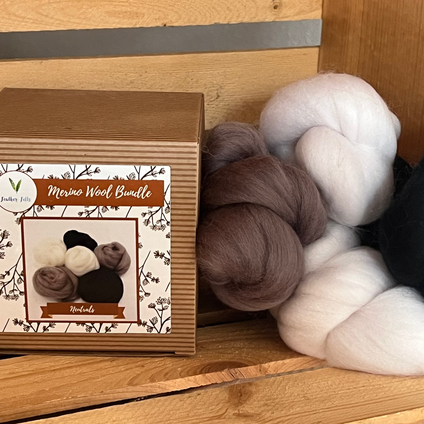 felted wool coming in white black and brown on a wooden surface