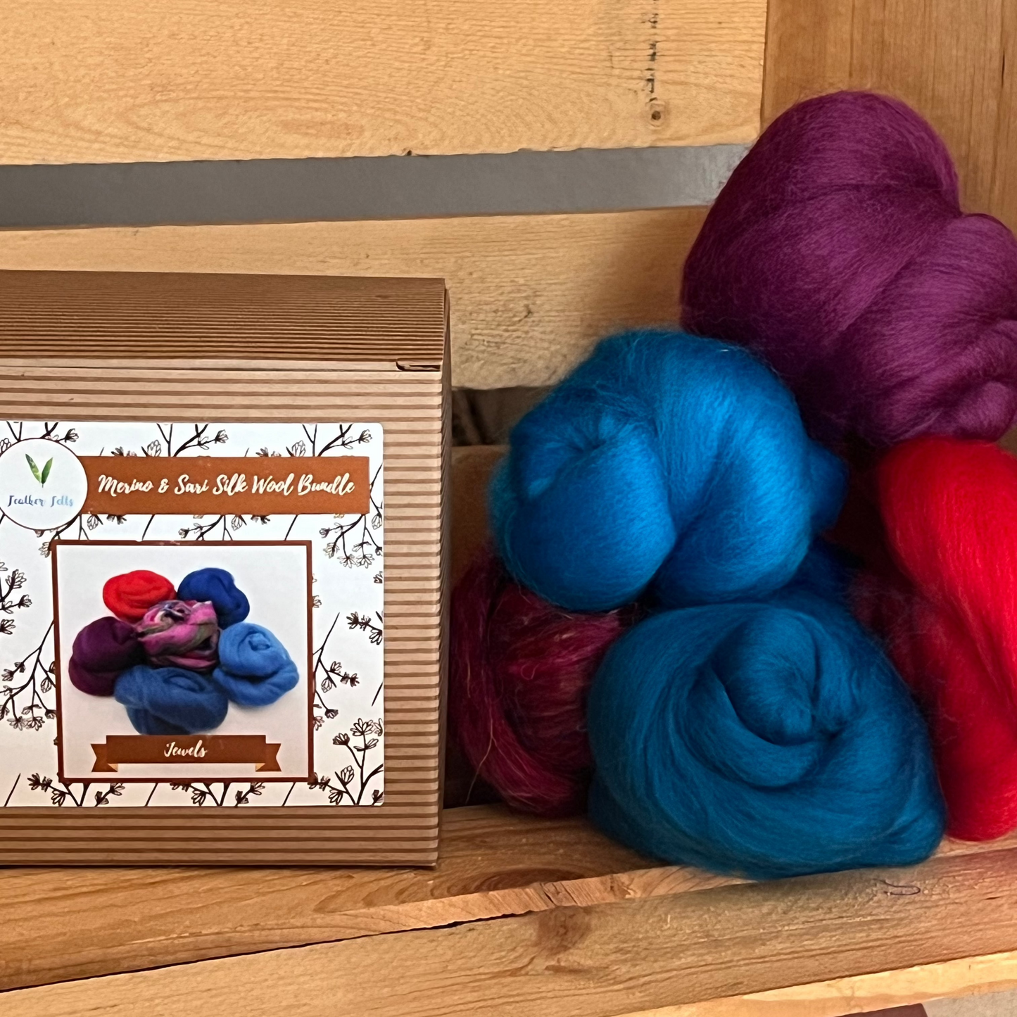 Felted wool in different colors like purple, red pink, and blues on a wooden surface