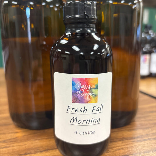 Bottle of 'Fresh Fall Morning' fragrence oils with a colorful label on a wooden surface