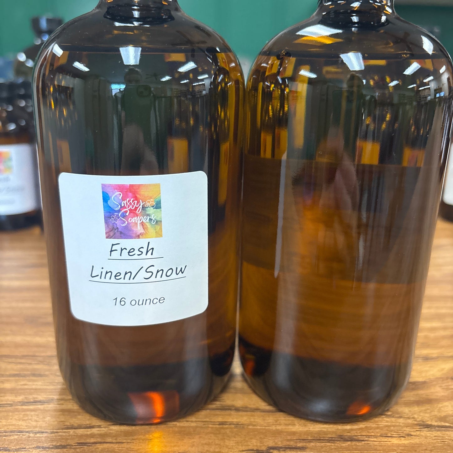 Two bottles of Fresh Linen Snow fragrence oils on a wooden surface with a colorful label.