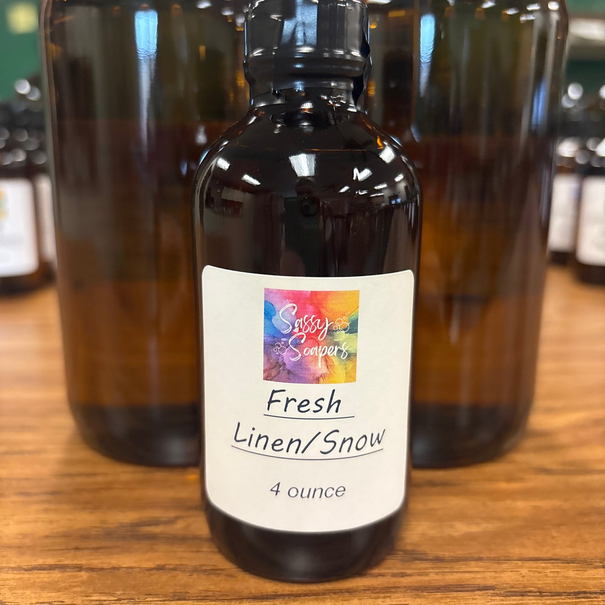 Bottle of 'Fresh Linen' fragrence oils with a colorful label on a wooden surface