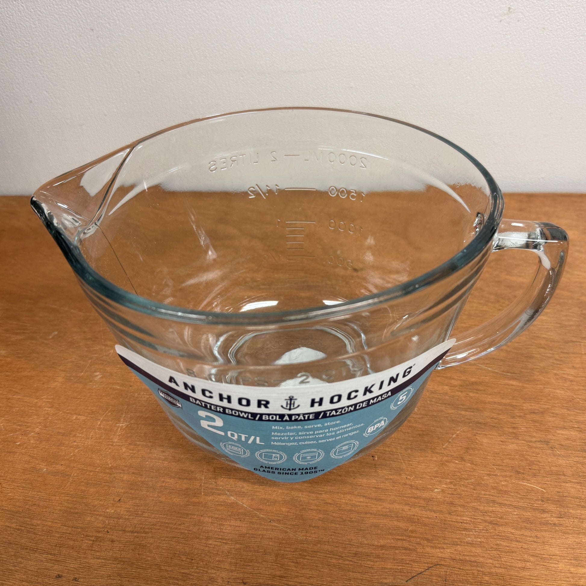 Clear glass mixing/measuring cup with handle on a wooden surface