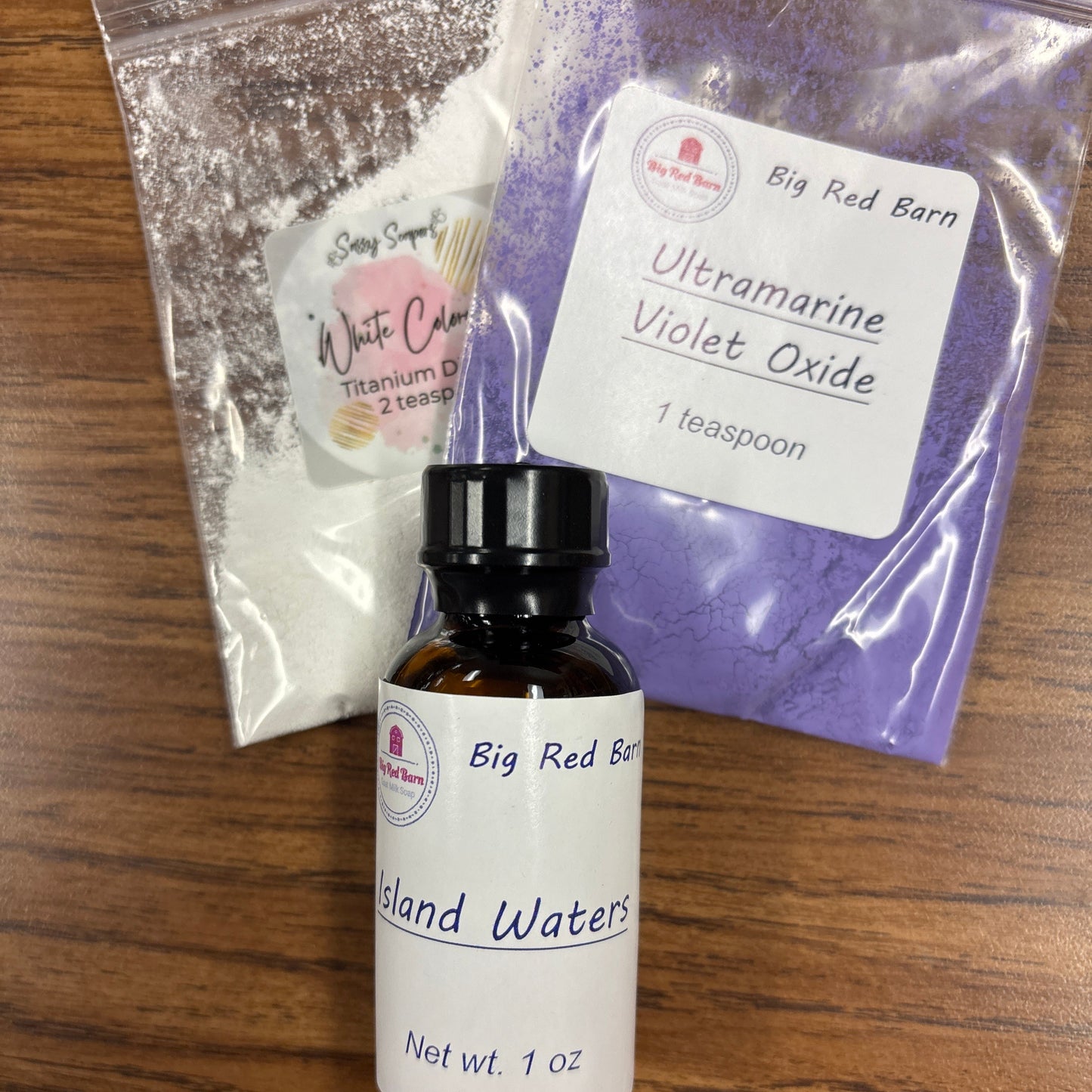 Bottle of 'Island Waters' with packets labeled 'White Color' and 'Ultramarine Violet Oxide' on a wooden surface.