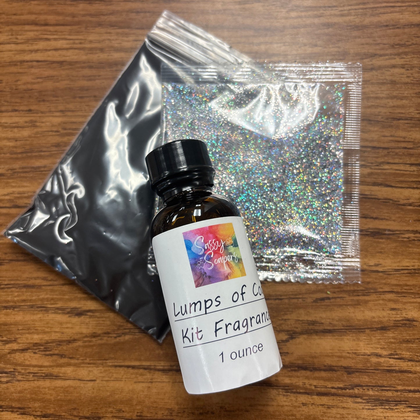 Fragrance kit with bottle, packaging, and glitter on a wooden surface