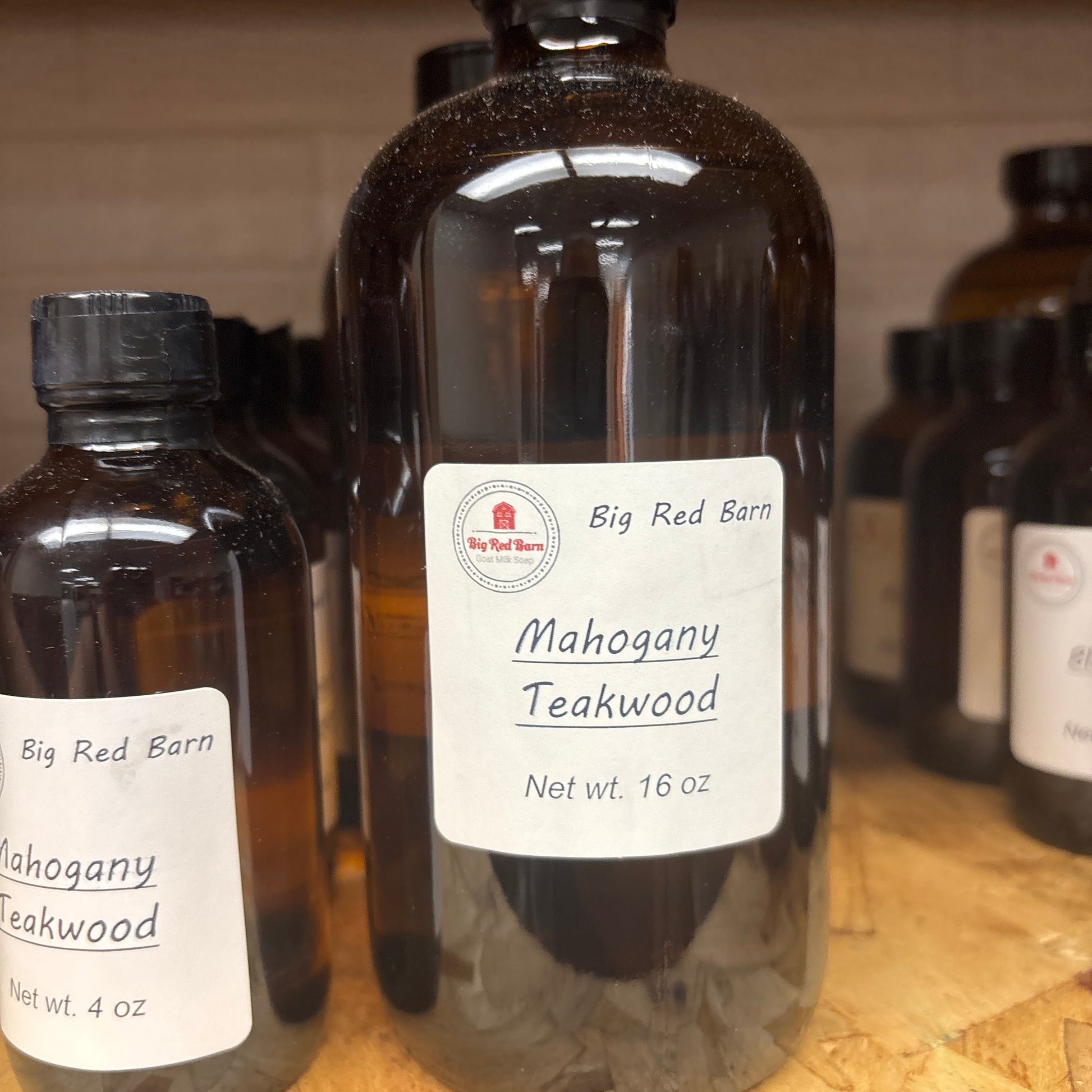 Two bottles of Big Red Barn Mahogany Teakwood fragrance on a wooden surface.