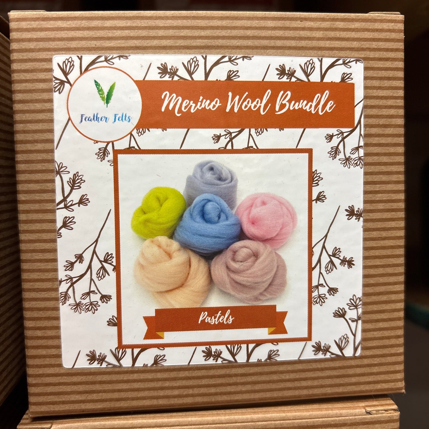 Cardboard box with a floral design and colorful wool bundles on a white background