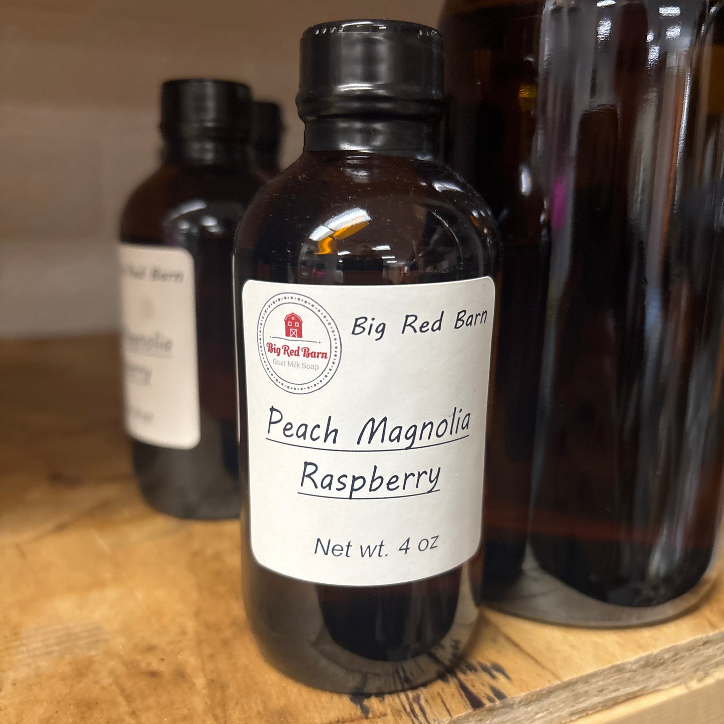 Bottle of Peach Magnolia Raspberry fragrence oils with a label on a wooden surface