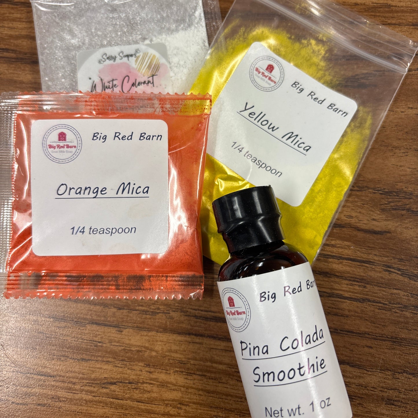 Assorted colorant packets and a bottle on a wooden surface