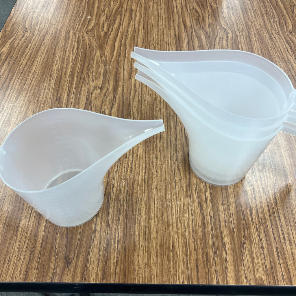 Set of white plastic pour pitchers on a wooden surface