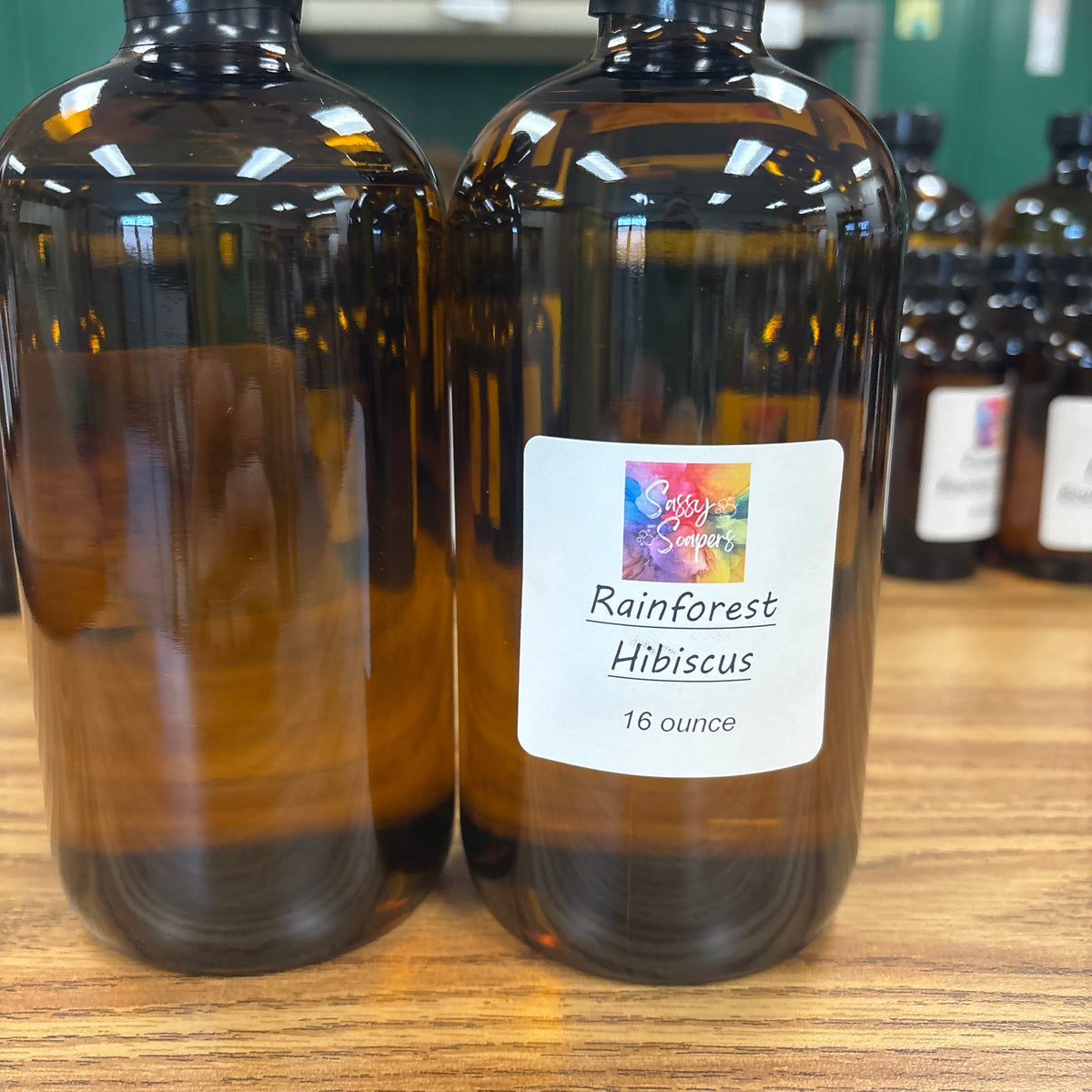 Two bottles of Rainforest Hillicus fragrence oils on a wooden surface with a blurred background.