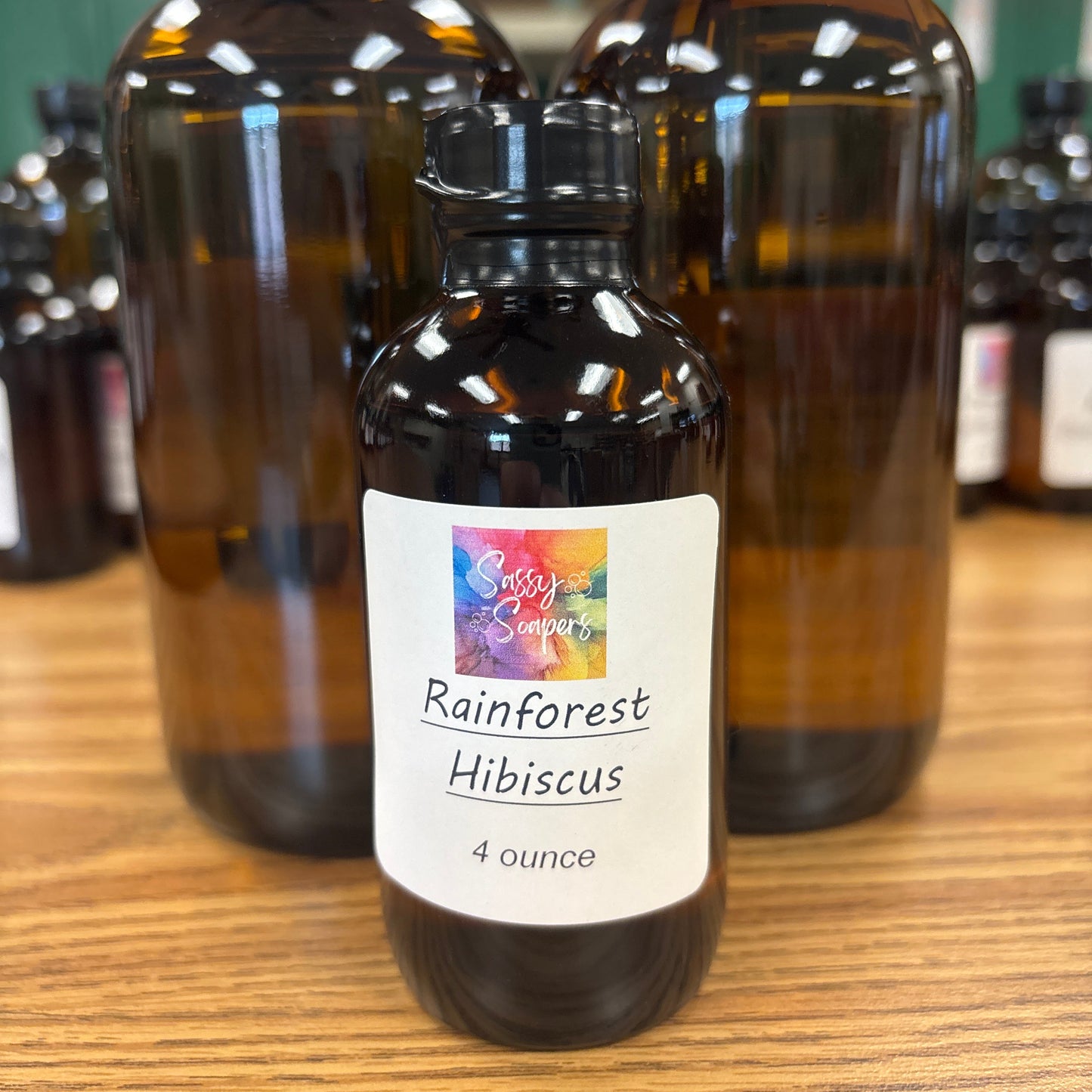 Two bottles of Rainforest Hibiscus fragrence oils on a wooden surface