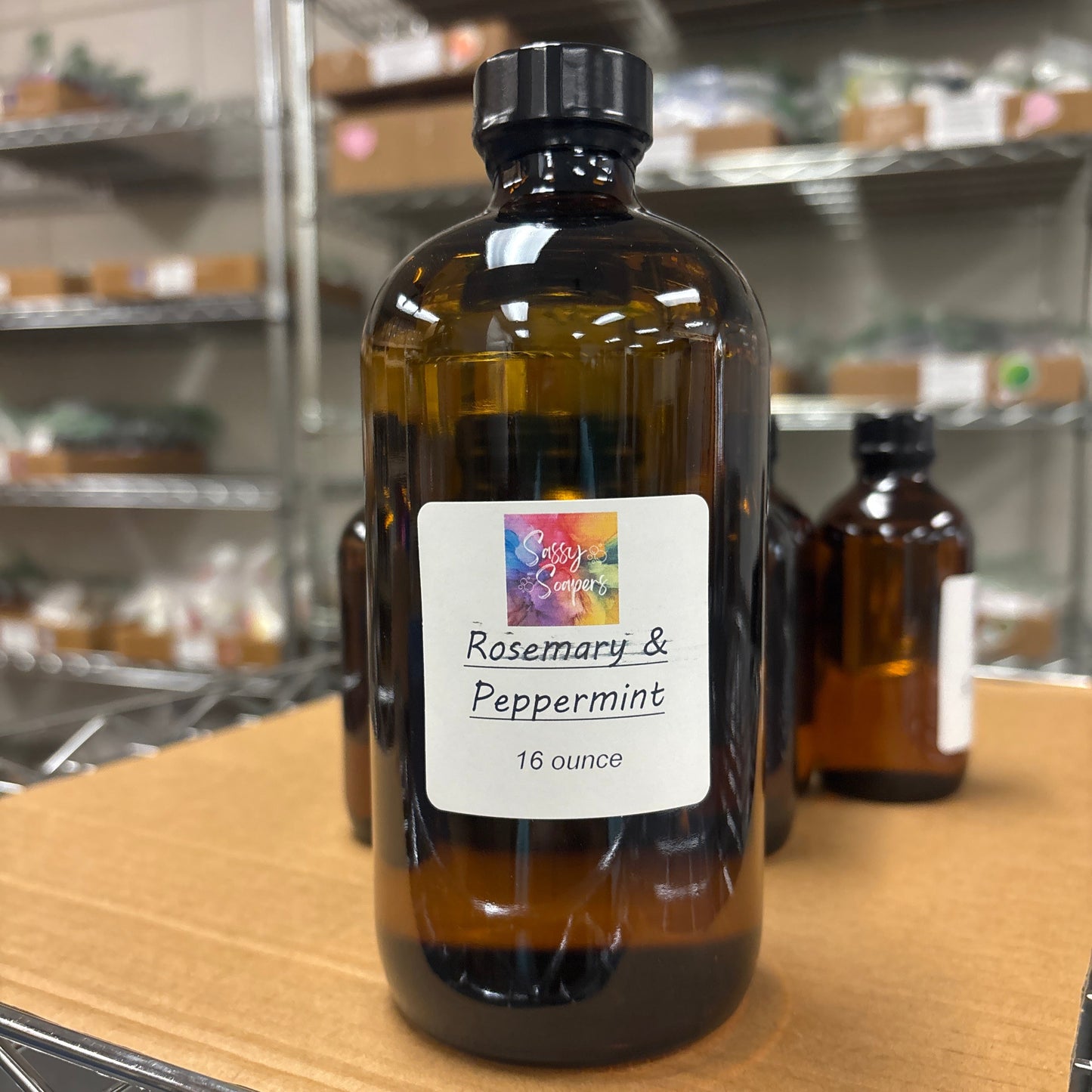 Bottle of Rosemary & Peppermint fragrence oil on a wooden surface with a blurred background