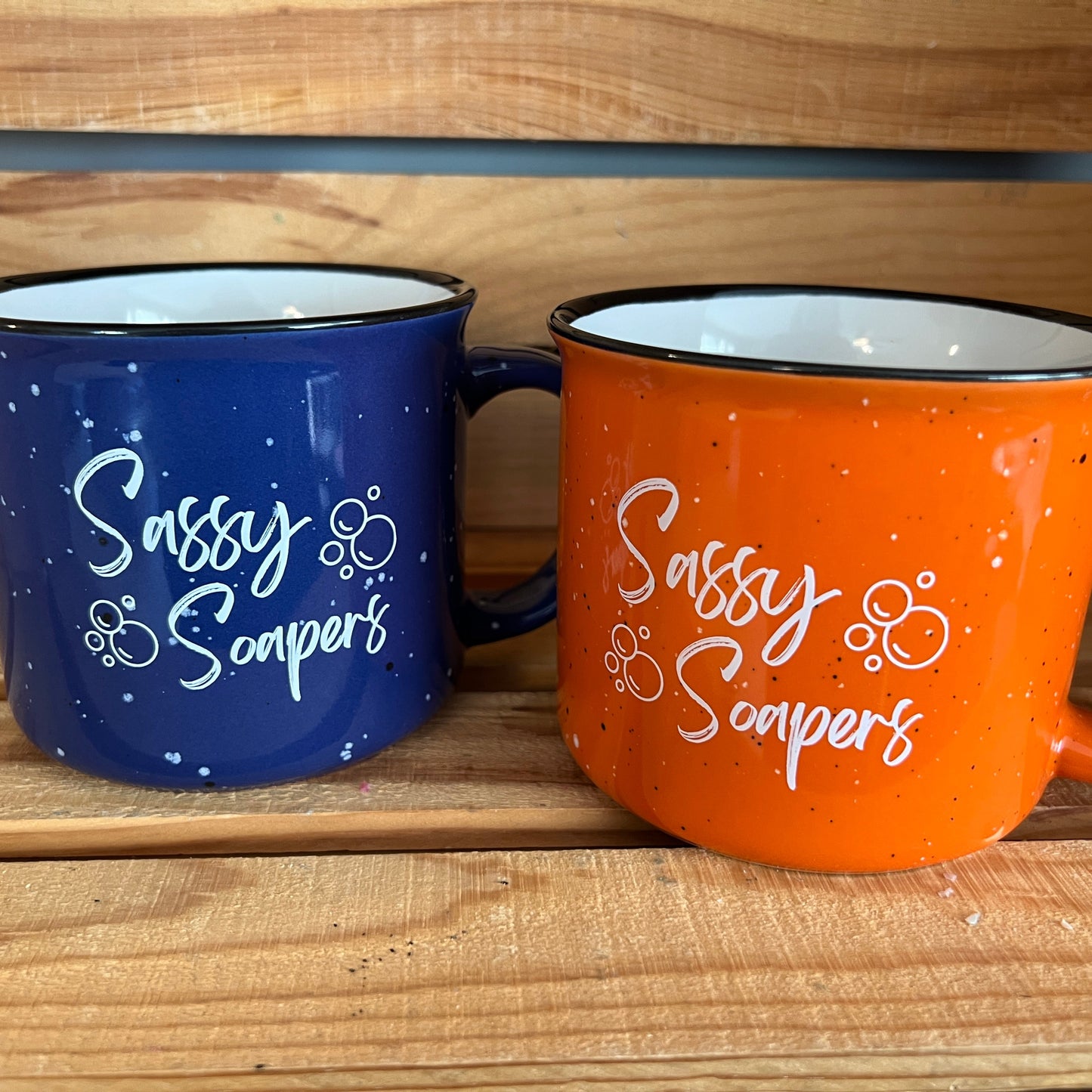 2 mugs sitting on a wooden shelf