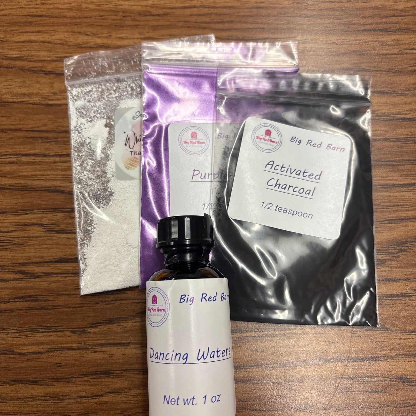 School Pride kit  products including an Dancing Waters fragrence oil bottle and colorant packets on a wooden surface