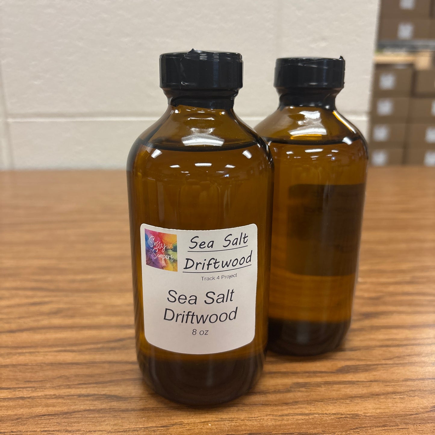 Two brown bottles with Sea salt Driftwood fragrence labels on a wooden surface