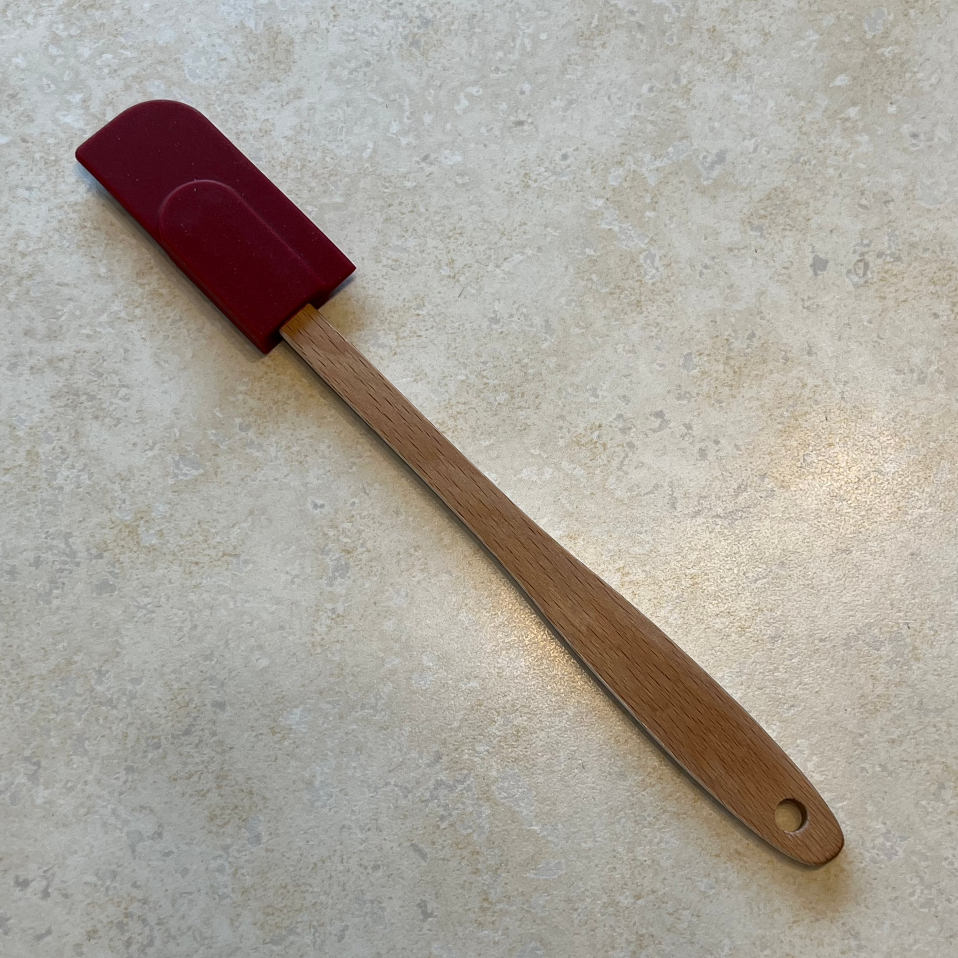 Small red rubber spatula with wooden handle