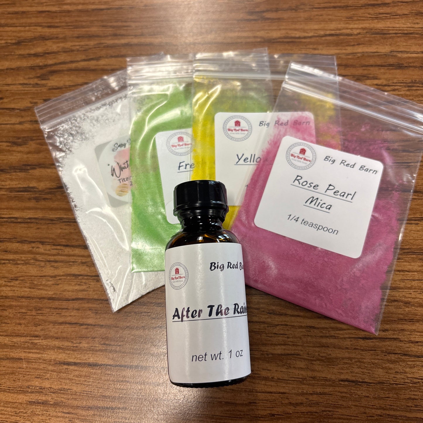 Assorted beauty products including After the Rain fragrence bottle, colorant packets, and a mask on a wooden surface.