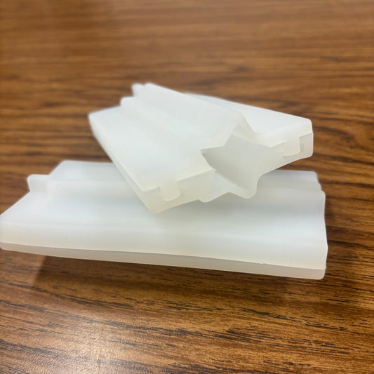 Two white plastic molds designed for crafting embeds, placed on a wooden surface.