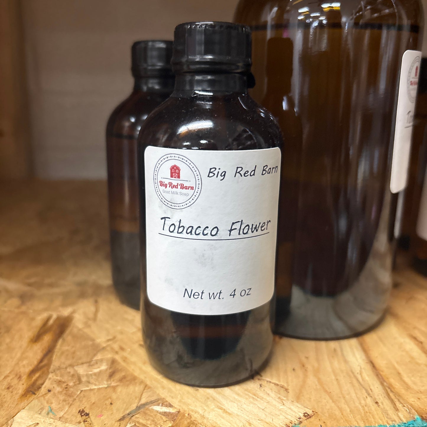 Two dark glass bottles with Tabacco Flower fragrence oils labels on a wooden surface