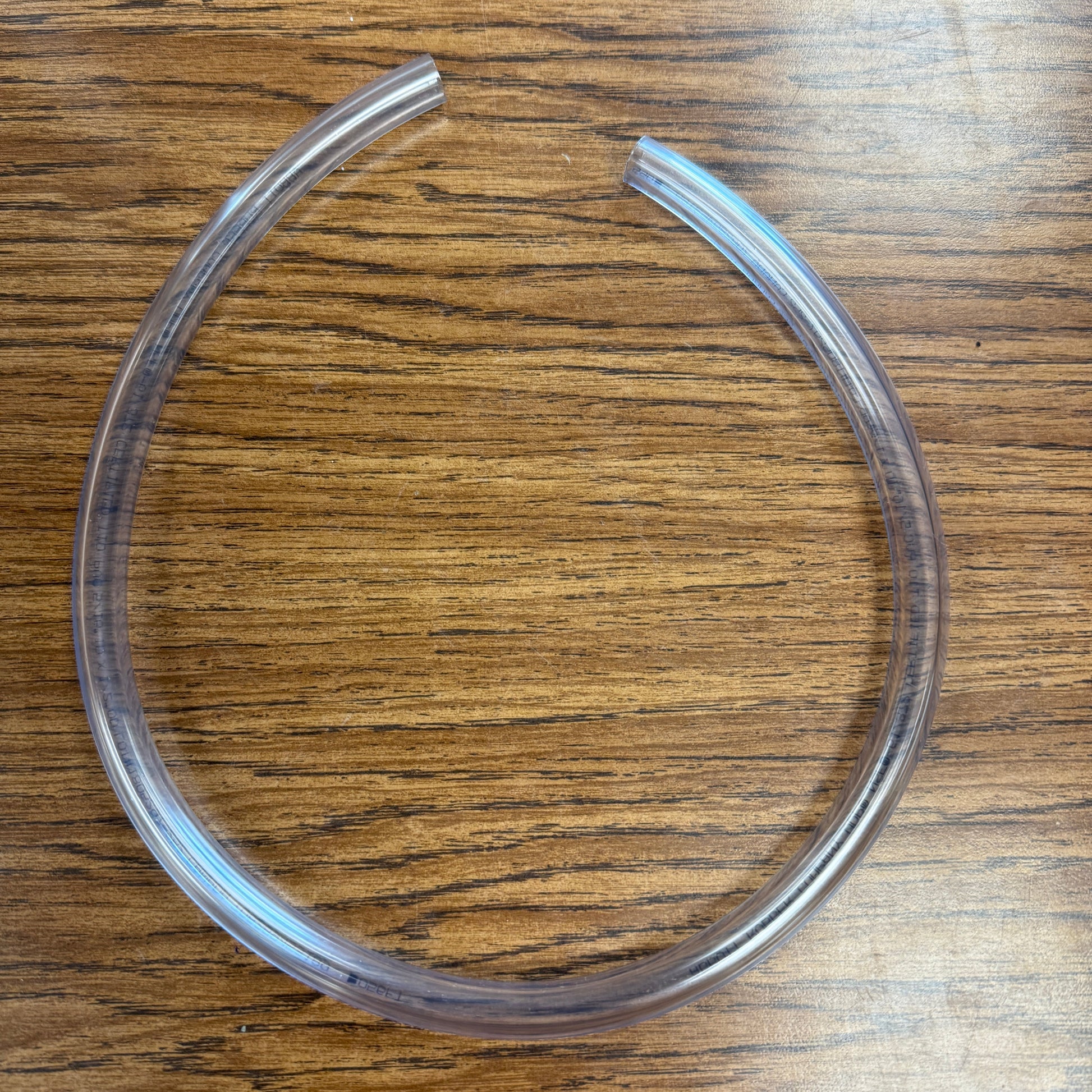 A clear, circular, fat-swirl tool for making soap, displayed on a wooden surface.