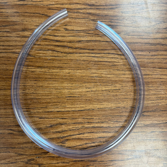 A clear, circular, fat-swirl tool for making soap, displayed on a wooden surface.
