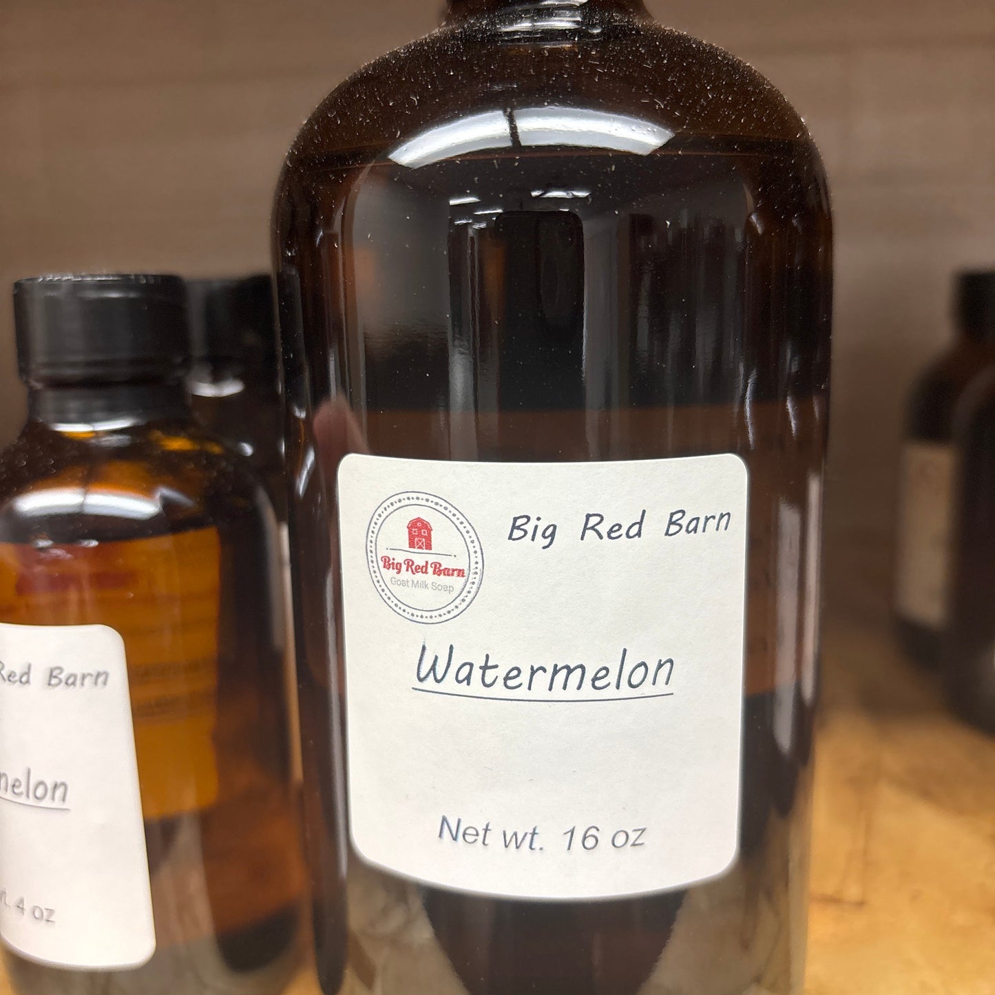 Bottle of Big Red Barn Watermelon fragrance with a label on a wooden surface.