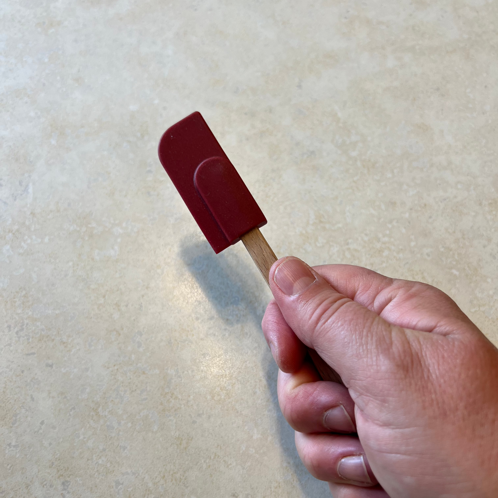 small wooden spatula with red rubber at the end