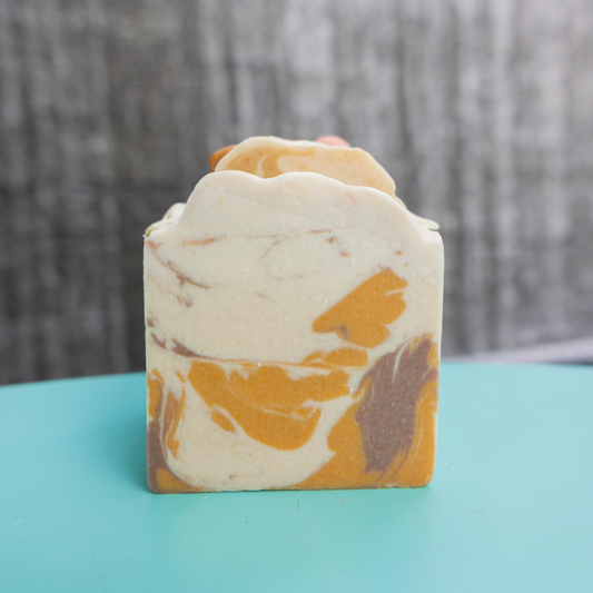 Marbled soap bar with orange and brown patterns on a teal surface